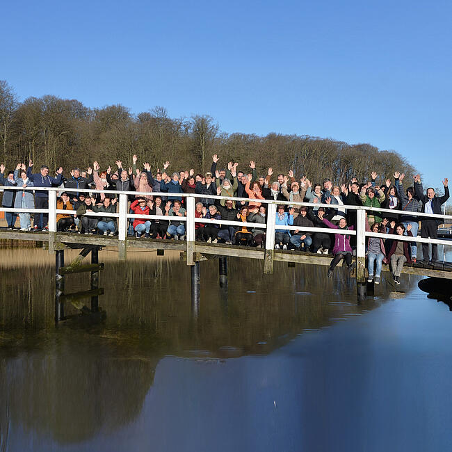 Teamfoto (rund 50 Personen) der Brücke Flensburg auf einer Brücke bei Sonnenschein